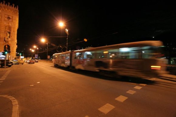 Miljacka nehri kıyısında gece giden bir tramvay.