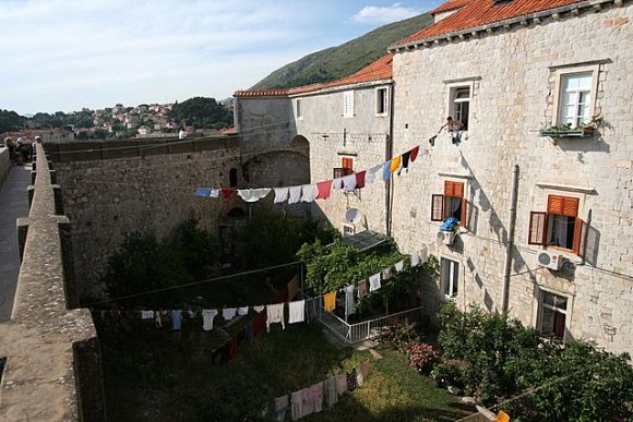 Şehir duvarlarının hemen dışında yaşayan insanlar var. Adamın biri çmaşırlerını topluyor.