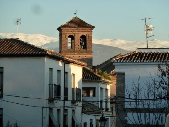 Albayzin'de bir sokak ve arkada Sierra Nevada dağlarının karlı zirveleri.