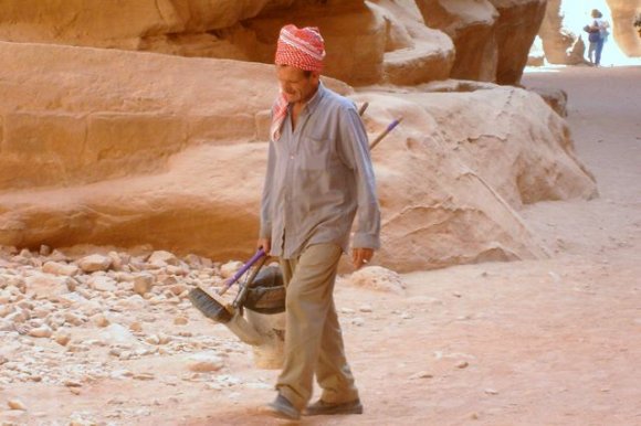 Siq geçidi boyunca çalisan bir temizlik isçisi. Turistlerin ve yol boyunca giden hayvanlarin biraktigi pislikler gun boyunca bu